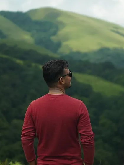 A trekker looking out at the vast green landscape of the Western Ghats.