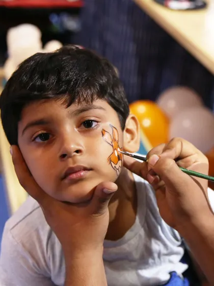 Face painting is always a huge hit at our parties. Here, a child gets a custom design, adding a touch of creative fun to our anniversary celebration.