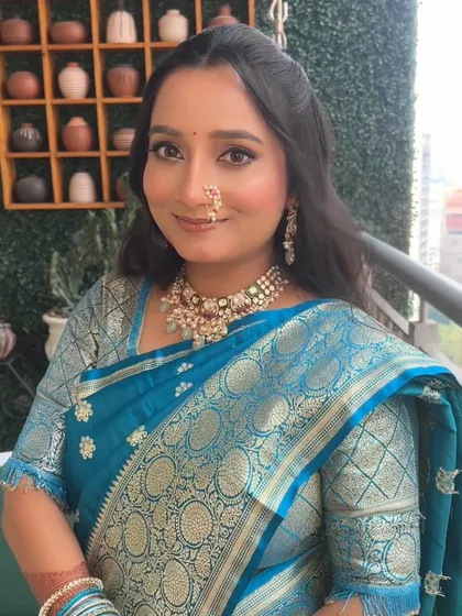 The complete engagement look in a beautiful blue saree. The makeup is balanced to complement the vibrant color of her outfit.