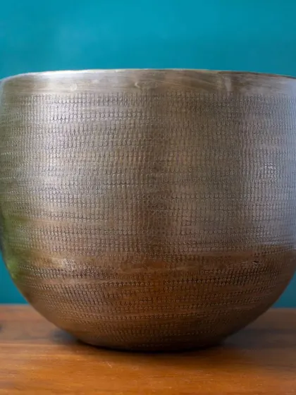The Advait Bronze Finish Planter features a subtle, hand-hammered texture that adds visual interest without overwhelming the plant it holds. It's a piece that exudes quiet elegance.