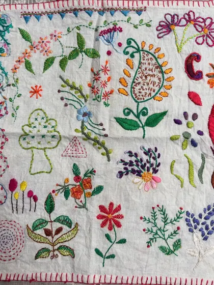 A beautiful freestyle sampler created by one of my students. After learning various stitches, she planned and executed this project, filling the fabric with colorful flowers, leaves, and a central paisley motif.