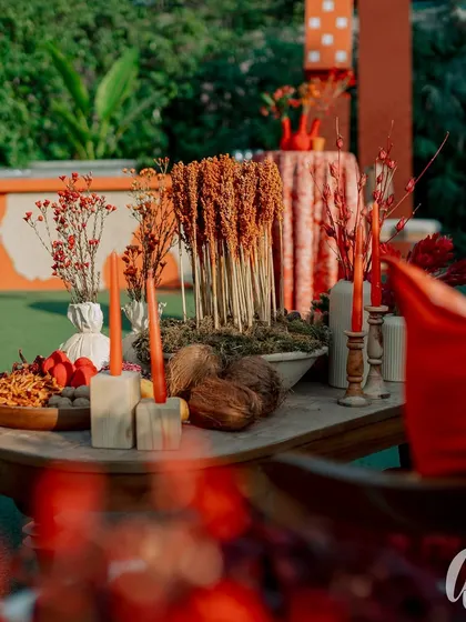 A detail shot of a lounge table centerpiece, featuring dried and fresh botanicals in shades of orange and red. The arrangement is both rustic and sophisticated, perfectly matching the event's theme.
