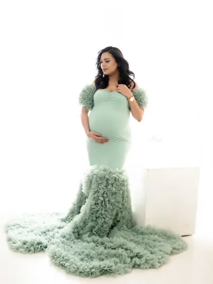 A full-length portrait showing off the incredible detail of this mint green ruffled gown. The simple white background keeps all the focus on the mom-to-be.