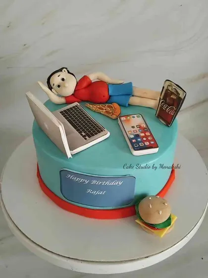 For someone who loves to work and eat. This cake features a figurine relaxing with a laptop, phone, pizza, burger, and a bottle of coke.