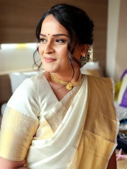 A stunning portrait of a bride in a traditional white and gold Kasavu saree, her makeup elegant and understated.