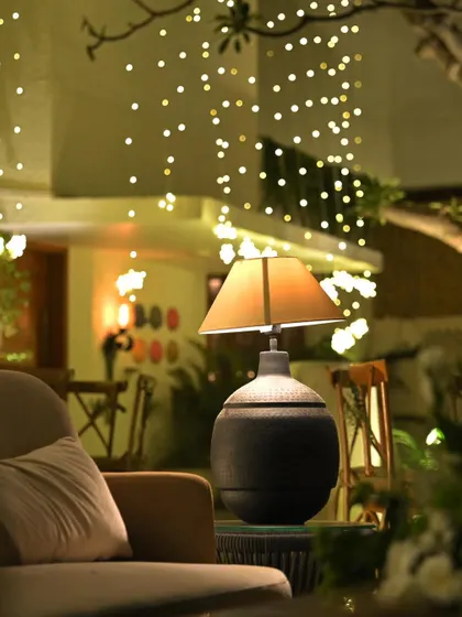 A cozy seating area outdoors, with a stylish lamp on a side table and a curtain of fairy lights in the background. This setup is perfect for intimate conversations.