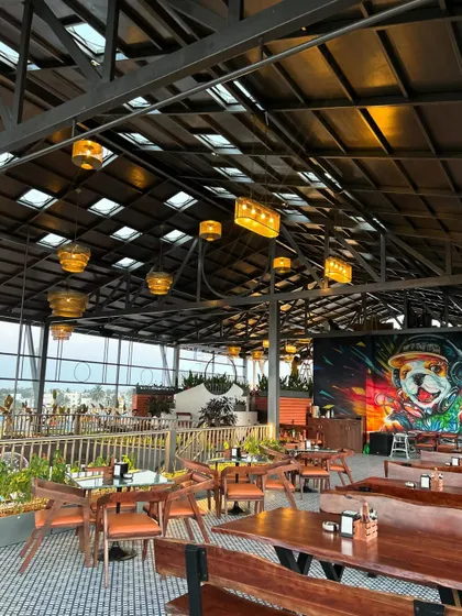 A wide shot of 'The Soda Factory' interior, showcasing the vibrant graffiti wall and the overall layout. Our landscaping work, including the planters and greenery, helps to soften the industrial architecture and create a lively atmosphere.