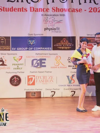 A student being felicitated on stage for her performance.