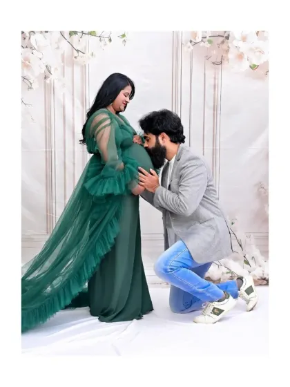 A heartwarming moment where the father-to-be kisses the baby bump. The mom-to-be looks angelic in the green tulle gown, creating a beautiful and emotional family portrait.