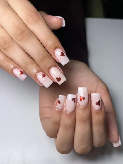 Soft, sweet, and a touch of romance. These milky white nails with dainty red hearts are perfect for Valentine's Day or any time you're feeling the love.