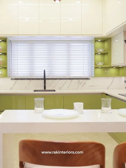 This kitchen features a refreshing combination of light green and white cabinets. The design includes a breakfast counter and ample storage, with a marble-patterned backsplash adding a touch of elegance.