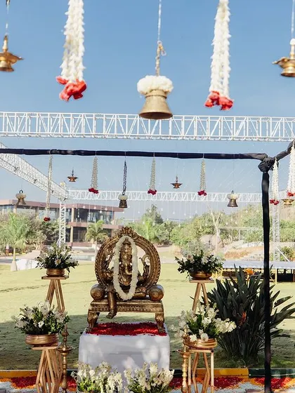 A simple mandap setup for a Ganesha puja, with hanging bells and floral decor.
