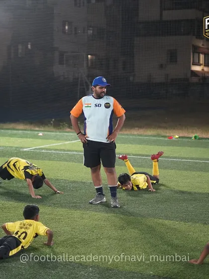 A coach supervises a group of young players during a core conditioning exercise. Fitness and strength are just as important as ball skills in my academy.