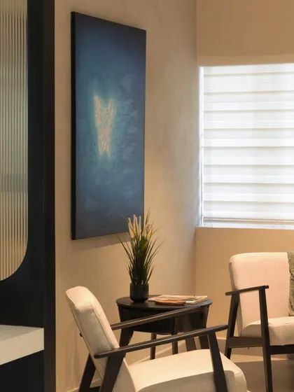 A detail of the lounge area, showing the texture of the rustic wall finish next to the soft upholstery of the chairs. This corner demonstrates how combining different textures can add depth and comfort to a modern office interior.