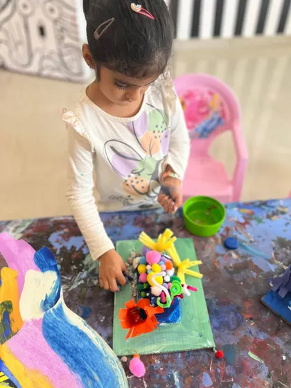 A young artist completely absorbed in her 3D collage work. Our camps encourage exploration with different textures and materials, like clay, yarn, and natural elements, to build fine motor skills and sensory awareness.