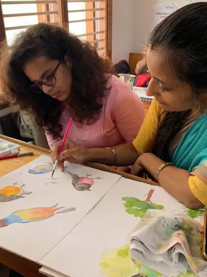 I guide a student as she practices painting birds in watercolor. These sessions are interactive, allowing for immediate questions and corrections, which accelerates the learning process.