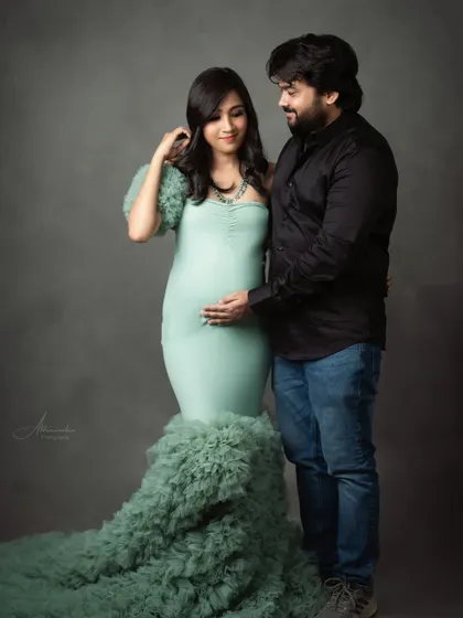 A tender moment between the expecting couple. The soft lighting and their gentle interaction make this a warm and loving portrait.