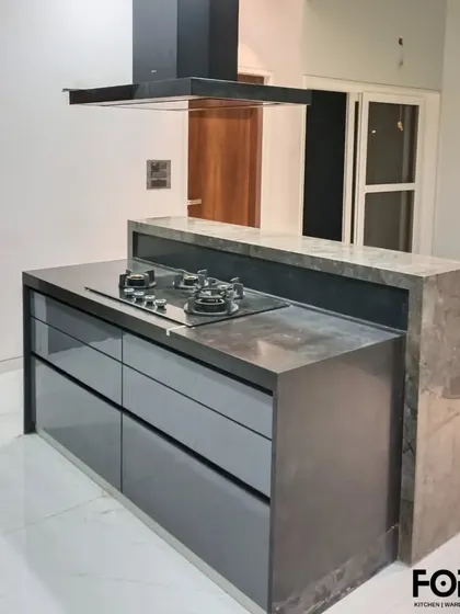 The kitchen island doubles as a cooking station with a built-in hob and drawers for storage. This design is perfect for those who love to cook and entertain at the same time.