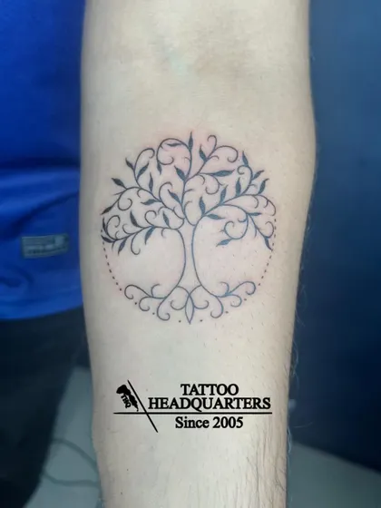 A beautiful "tree of life" tattoo with swirling branches and roots contained within a dotted circle.