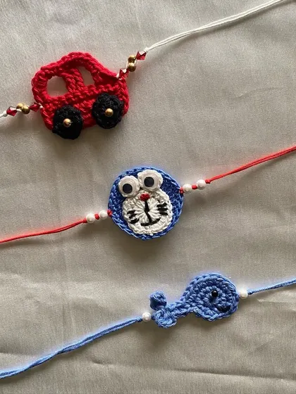 A collection of our crochet kid's rakhis, featuring a car, a Doraemon character, and a whale. We love creating these playful designs that kids will be excited to wear.
