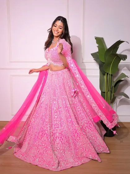 See the beautiful flare of our bright pink lehenga. The flowing dupatta adds a touch of grace to this dazzling and playful outfit.