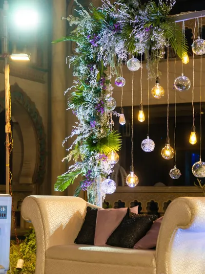 A detail shot of the elegant seating area, with a beautiful floral arrangement featuring hanging glass orbs and Edison bulbs that created a warm, inviting glow.