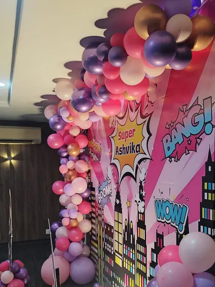 A detailed view of the balloon garland from the super-girl themed party, showing a mix of pink, purple, and metallic rose gold balloons.