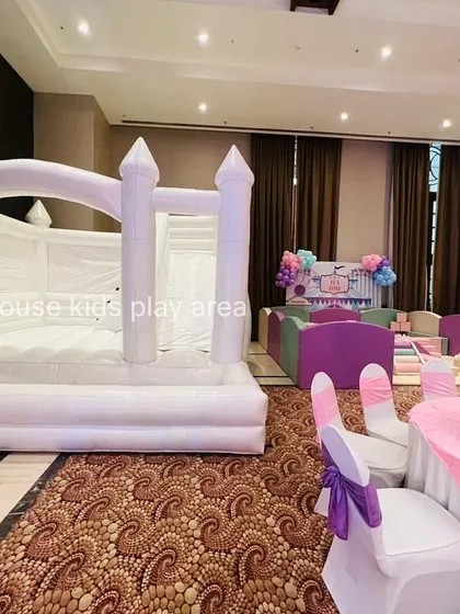 Our white bouncy castle set up indoors next to a pastel play area for a large party.
