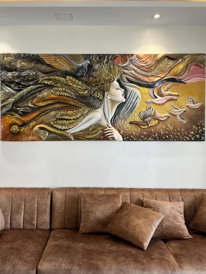 The "Self Love" mural installed above a sofa. This large-scale piece depicts a woman with hair made of feathers, surrounded by birds, symbolizing freedom and inner beauty.