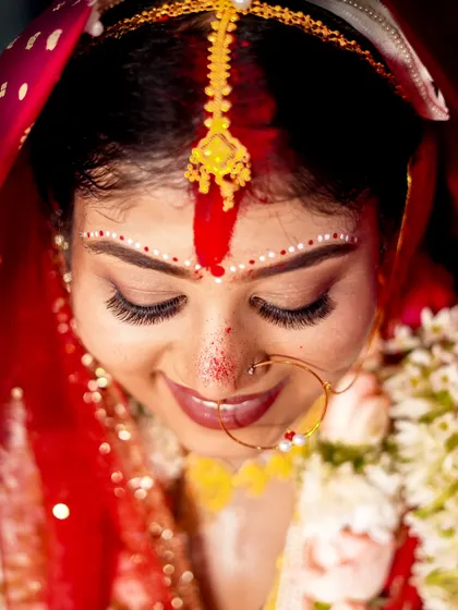 An artistic top-down shot of the Bengali bride, highlighting the intricate details of her makeup and the red veil.