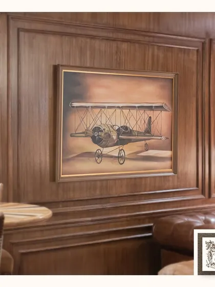 This vintage biplane painting adds a touch of aviation history and adventure to this classic, wood-paneled room. It's a sophisticated piece for anyone who appreciates retro design and exploration.