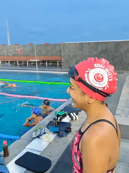One of our swimmers smiling proudly in her new red NMSA cap. It's more than just a cap; it's a symbol of being part of the team.