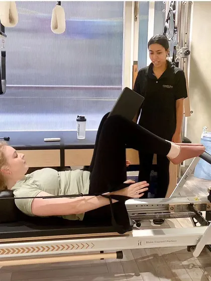 A private session in progress. Our instructor guides a client through a footwork series on the Reformer, ensuring proper alignment and engagement.