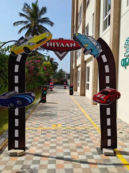 I create immersive entrances, like this custom-made racing arch for Niyaan's party. The arch is designed to look like a race track with cars speeding along it, creating an exciting welcome for guests.