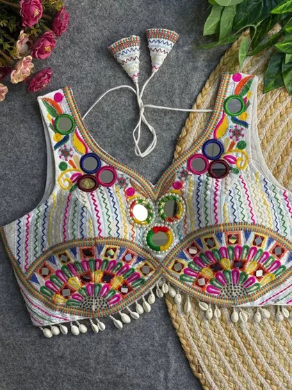 This is one of my favorite statement blouses. The combination of multi-color threadwork, mirror embellishments, and cowrie shell details makes it a standout piece you can pair with many different skirts.