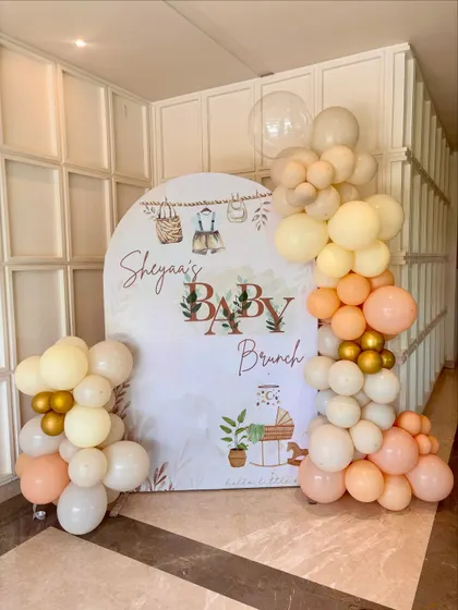 A closer look at the welcome sign and backdrop for Sheyaa's baby brunch. The custom-printed backdrop features charming illustrations that perfectly match the soft, neutral color scheme of the balloons.
