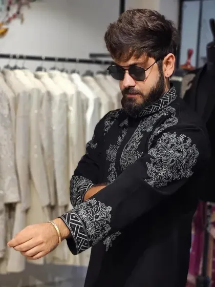A client trying on a black kurta with bold, white threadwork embroidery. The design is modern and graphic, perfect for a stylish man.