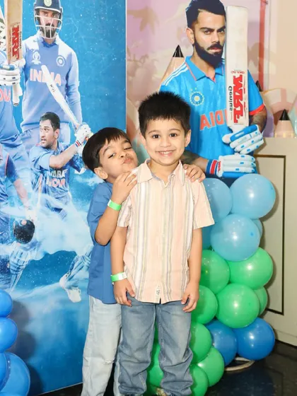 Two young guests have fun posing in front of the cricket-themed party backdrop.