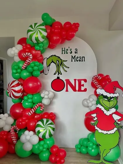 "He's a Mean ONE!" A fun Grinch-themed first birthday or Christmas party. This creative setup features the iconic character and a red and green balloon arch.