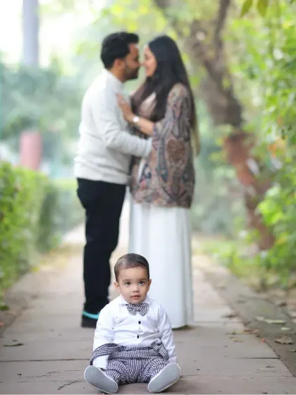 A beautiful family portrait with the baby in focus. The soft, natural background of the park creates a lovely, gentle mood for the photo.