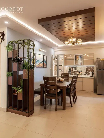 A spacious dining and kitchen area with a dark wood dining set and a green plant divider. The open-plan layout is perfect for modern family living, connecting the different zones of the home.