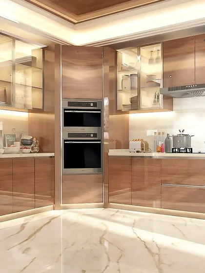 This luxurious kitchen combines glossy wood-finish cabinets with built-in double ovens and a large side-by-side refrigerator. The under-cabinet and in-cabinet lighting adds a warm, ambient glow.