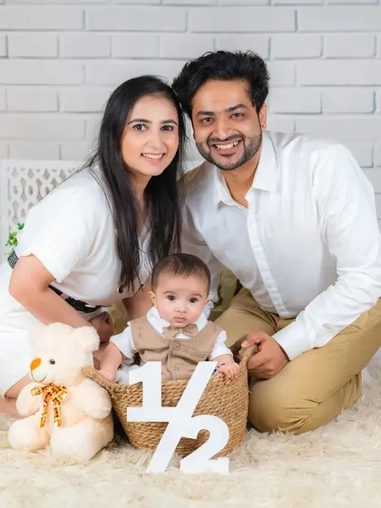 A perfect family photo celebrating a baby's half-birthday. The family is gathered around the baby, who sits in a basket next to a "1/2" sign.