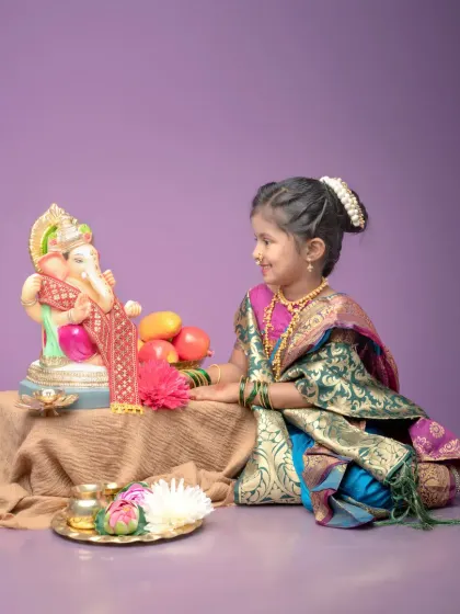 A beautiful side profile of the little girl as she looks lovingly at the Ganpati idol. This shot captures a moment of pure devotion and innocence.