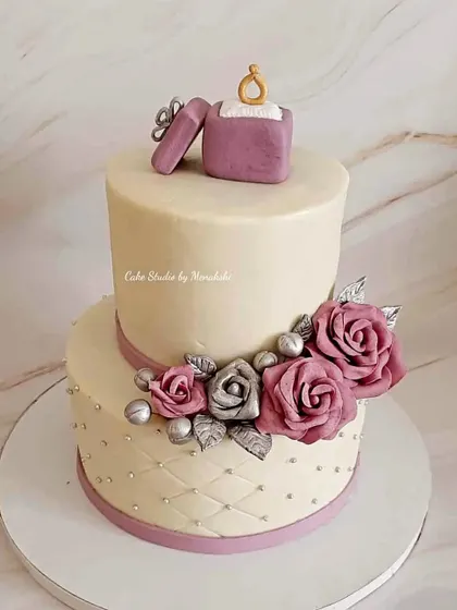 A classic engagement cake with a modern twist. This two-tier design features a quilted bottom layer and is decorated with handmade sugar flowers in lavender and silver to match the bride's dress.
