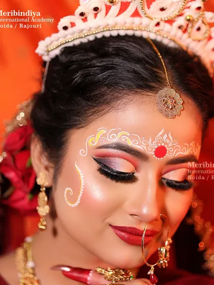 A beautiful portrait of the Bengali bride, showcasing the neat bun decorated with flowers and the traditional makeup artistry taught in our course.