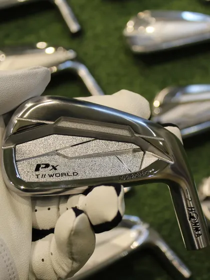 A close-up of the beautifully crafted Honma PX T//World iron, held in a gloved hand.