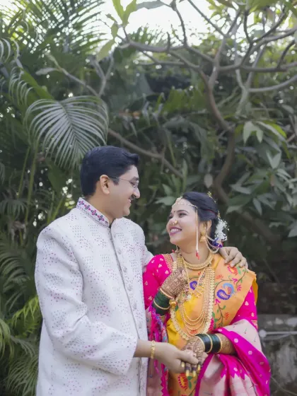 A sweet, candid moment between the bride and groom, sharing a look of love amidst the greenery after their ceremony.