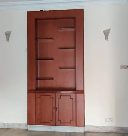 The 'before' shot of a living room, showing a bulky, dark wood cabinet that closed off a small window and made the room feel dated.