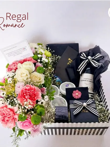 A closer look at our 'Regal Romance' hamper, showcasing the elegant black and white striped box, fresh carnations and roses, and a hand-selected bottle of Malbec.